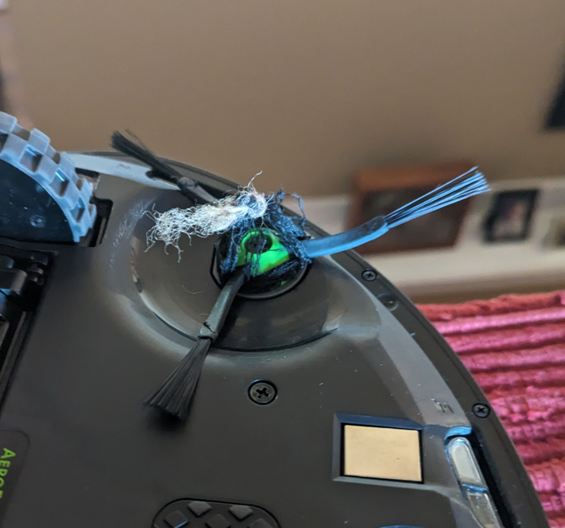 Underside view of Roomba with thread wrapped around whisking brush